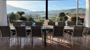 A covered outdoor dining area with a view of a mountainous landscape.