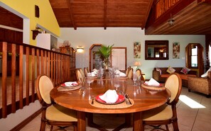 A dining area with a wooden table set for six, surrounded by wicker chairs.
