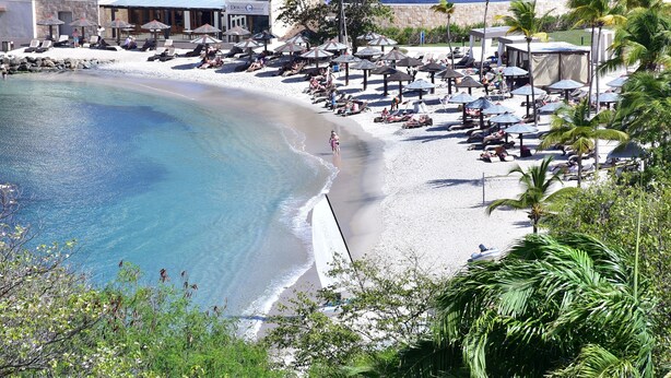A beach resort with sun loungers, umbrellas, and a clear blue pool. - Villa Gina Beachfront Villa  (Cap estate)