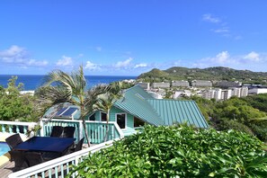 Ein Resort mit Pool, Sitzgelegenheiten im Freien und Blick auf den Ozean und die Hügel.