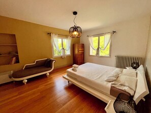 Una camera da letto con un letto, un divano, un termosifone e una finestra con tende.
