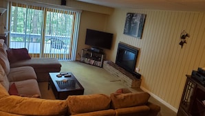 A living room with a sectional sofa, a flat-screen TV, a fireplace, and a bookshelf. - Spectacular Seven Springs Skiing and golfing in Pennsylvania (Champion)