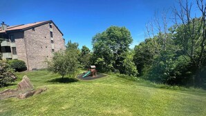 A grassy yard with a playground, trees, and a building in the background. - Spectacular Seven Springs Skiing and golfing in Pennsylvania (Champion)
