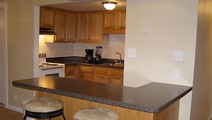 A kitchen with wooden cabinets, a granite countertop, and two stools. - Spectacular Seven Springs Skiing and golfing in Pennsylvania (Champion)