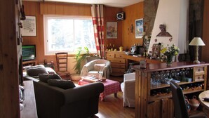 Un salon chaleureux avec une cheminée, des meubles en bois et un coin repas avec une table mise pour deux personnes.
