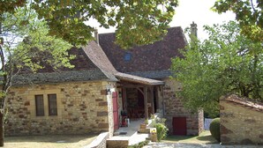 Ein Steinhaus mit geneigtem Dach und einer Veranda.
