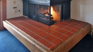 A fireplace with a herringbone wood panel design, a tiled hearth, and a visible fire. - IMMACULATE 3BR SKI TOWNHOME INSIDE NORTHSTAR RESORT! (Truckee)