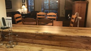 A wooden dining table with four chairs, a fireplace, a fan, and a view of a snowy landscape through a window. - IMMACULATE 3BR SKI TOWNHOME INSIDE NORTHSTAR RESORT! (Truckee)
