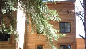 A wooden cabin with a central entrance, multiple windows, and a small porch area. - IMMACULATE 3BR SKI TOWNHOME INSIDE NORTHSTAR RESORT! (Truckee)