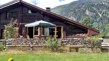 A rustic wooden cabin with a stone wall and a stone staircase leading to the entrance.