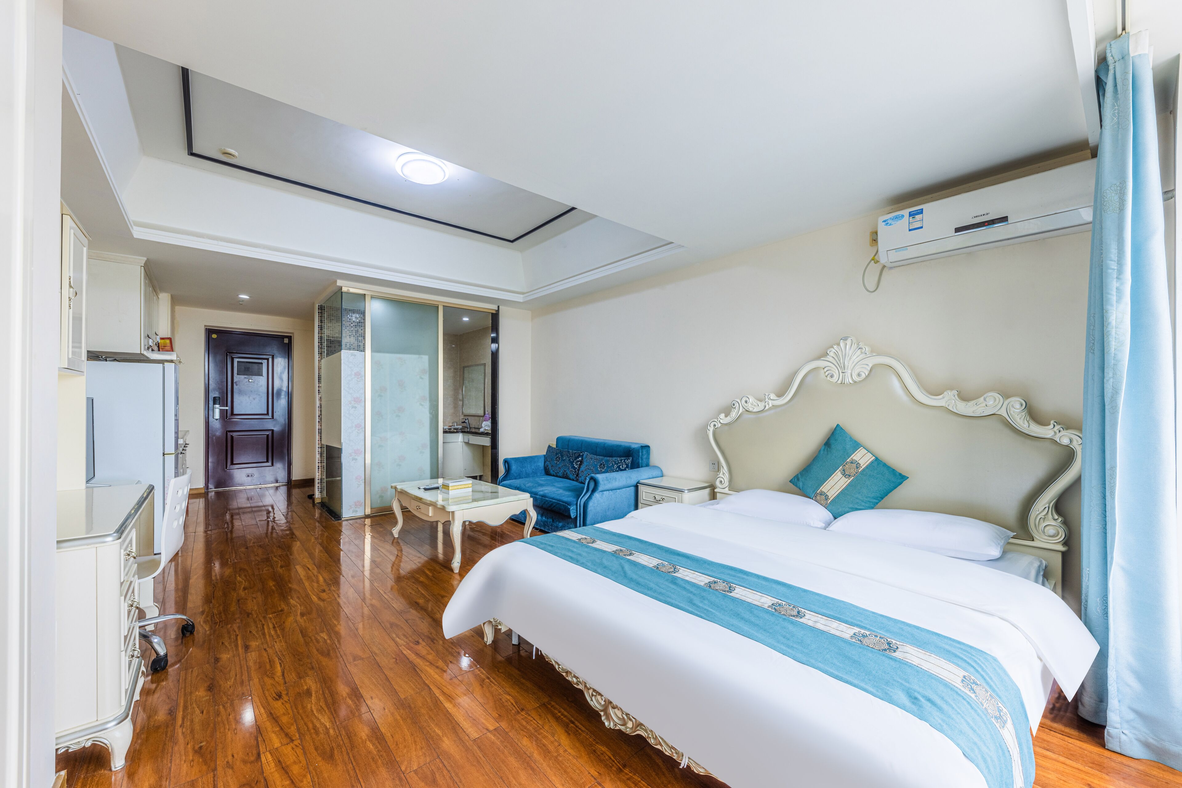 Une chambre d’hôtel avec un grand lit, un bureau, une chaise et un canapé bleu.