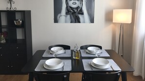 A dining area with a table set for four, a black and white portrait above the table, and a floor lamp to the right. - CENTER - SPACIOUS - COZY - WIFI (Albi)