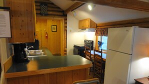A kitchen with wooden cabinets, a refrigerator, a stove, and a coffee maker. - WHISKEY SPRINGS CABINS #1
Cozy and delightful, in town convenience (West Yellowstone)