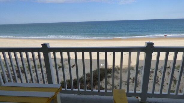 Blick auf einen Strand vom Balkon mit Geländer, mit Sandstrand und Meer.