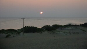 Ein Strand mit Sonnenuntergang, sandigem Untergrund und einem Strommast.