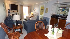 Ein Wohnzimmer mit Esstisch, Stühlen, Sofas und einem Fernseher.