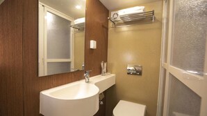 Ein Badezimmer mit weißem Waschbecken, Spiegel, Toilette und Duschbereich.