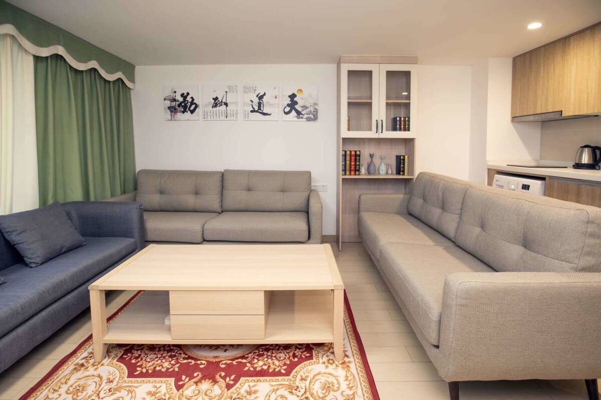 Una sala de estar con dos sofás, una mesa de centro y una estantería con libros y objetos decorativos.