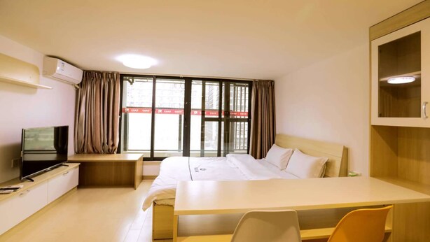 Ein Hotelzimmer mit Bett, Schreibtisch, Fernseher und einem Fenster mit Vorhängen.