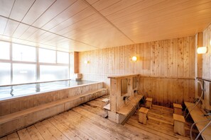 Una sauna de madera con un ventanal grande, bancos de madera y un baño de vapor.
