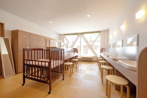 Una habitación infantil moderna con una cuna de madera, cambiadores y un amplio ventanal con luz natural.