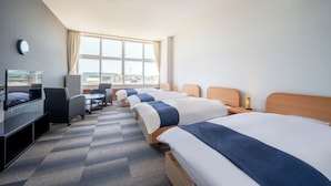 A hotel room with four beds, a TV, a desk, and a large window. - Kibotcha - Hostel (Higashimatsushima)