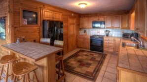 A compact kitchen with wooden cabinets, a refrigerator, a stove, and a microwave. - Mountain Top Private Retreat (todd)
