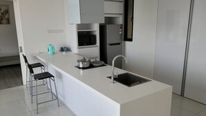 A modern kitchen with a central island, stainless steel appliances, and a minimalist design. - South Key Mosaic 19 (Johor Bahru)
