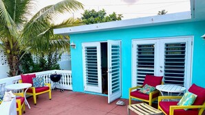A turquoise building with white shutters, outdoor seating with red cushions, and a palm tree. - Welcome to Coconut Cay *As Seen on HGTV (Vieques)