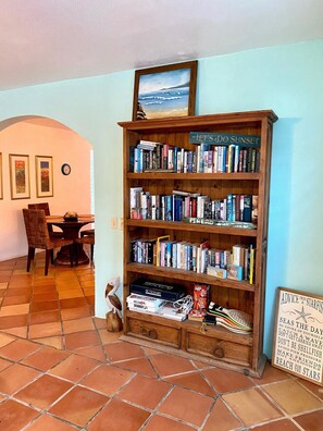 A room with a wooden bookshelf filled with books, a framed picture of a sunset, and a sign with advice from a starfish. - Welcome to Coconut Cay *As Seen on HGTV (Vieques)