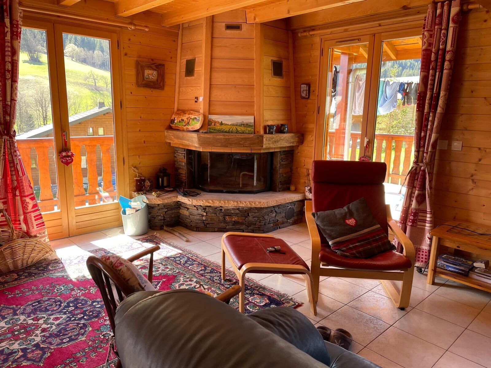 Ein gemütliches Blockhaus-Interieur mit Kamin aus Stein, Holzwänden und einem Balkon mit Holzgeländer.