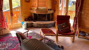 L’intérieur chaleureux d’un chalet avec une cheminée en pierre, des murs en bois et un balcon doté d’une balustrade en bois.
