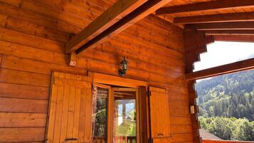 Une cabane en bois dotée d’un balcon donnant sur une vallée boisée.
