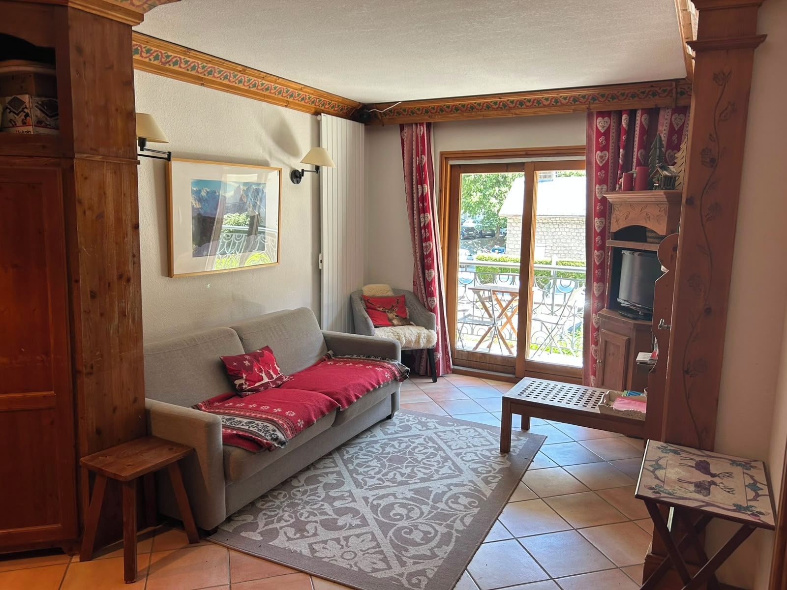 Un salon comprenant un canapé, un tapis à motifs, une petite table et une vue sur l’extérieur grâce à une porte vitrée.