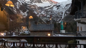 A mountain view with snow-covered peaks, a balcony with a metal railing, and a building with a stone facade. - Appart cozy 4/6 pers in residence hotel 4 *, TB located, calm, wifi, park (Chamonix-Mont-Blanc)