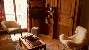 A cozy living room with a sofa, armchair, and a small table with books and a remote control. - Appart cozy 4/6 pers in residence hotel 4 *, TB located, calm, wifi, park (Chamonix-Mont-Blanc)