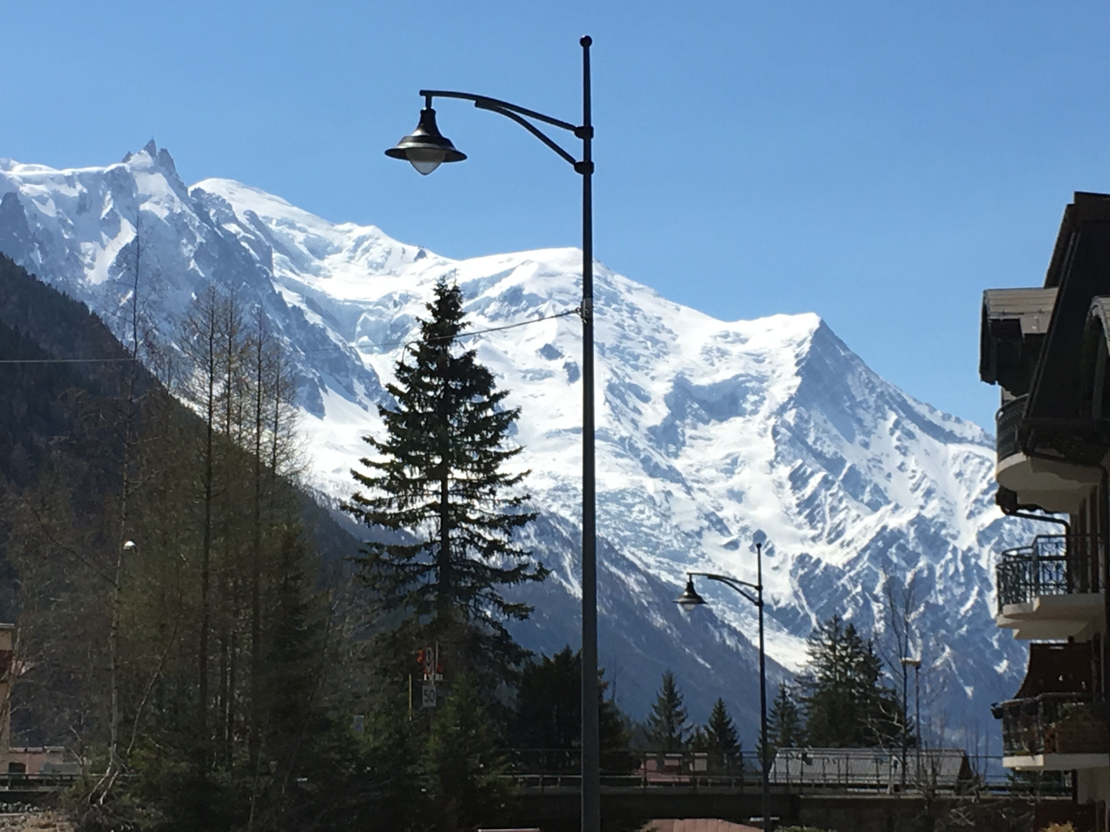 Eine Straße mit einem schneebedeckten Berg im Hintergrund, einer Straßenlaterne und einer Brücke.