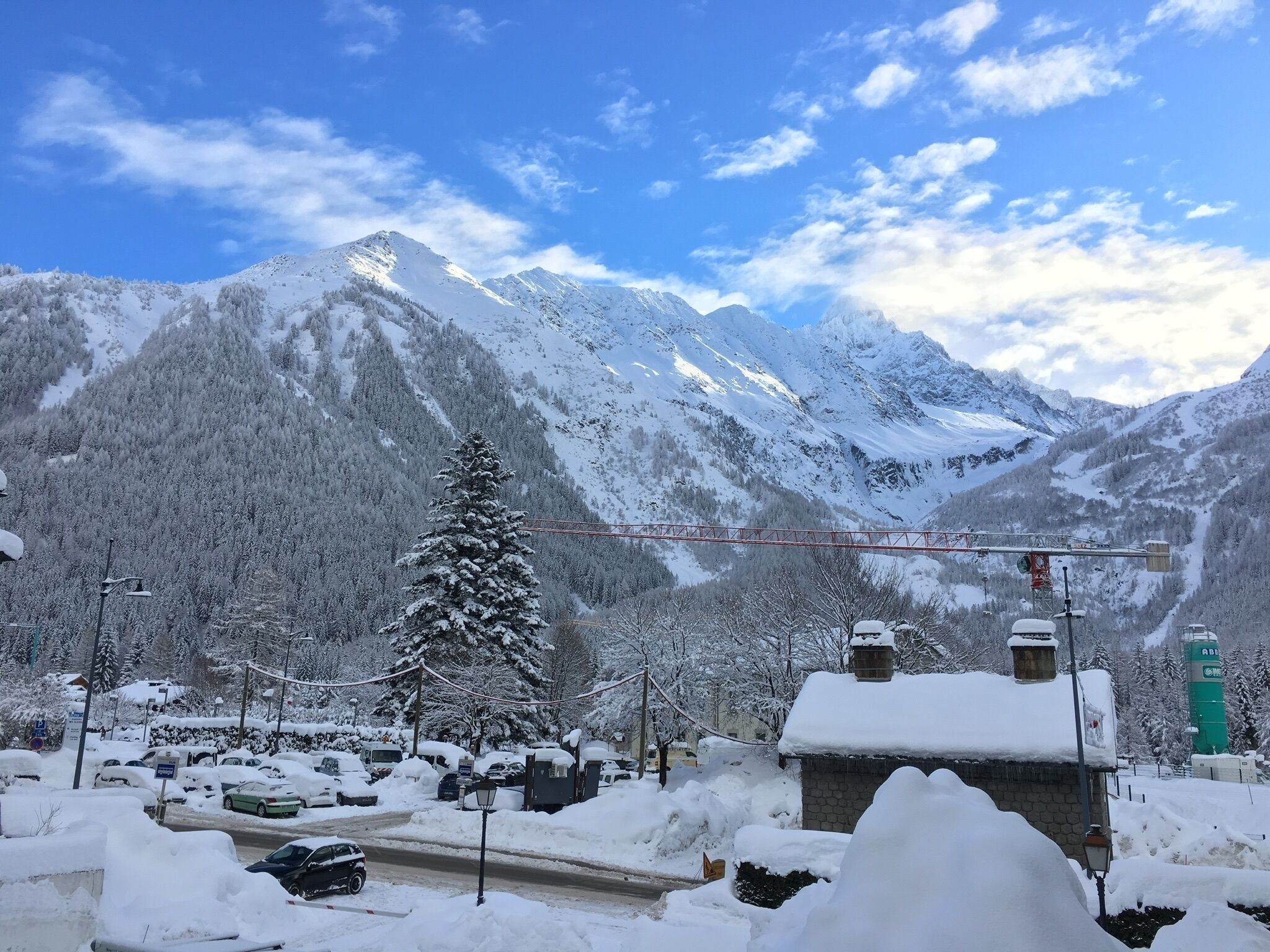 Eine verschneite Berglandschaft mit einem mit Schnee bedeckten Baum und einer Brücke.
