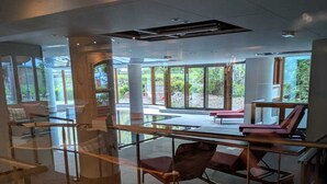A spacious indoor area with large windows, a glass railing, and a few lounge chairs. - Appart cozy 4/6 pers in residence hotel 4 *, TB located, calm, wifi, park (Chamonix-Mont-Blanc)