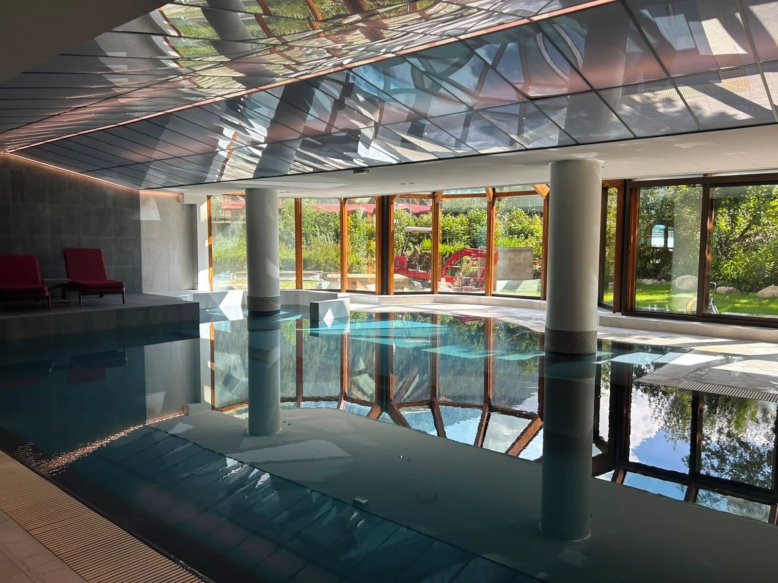 Ein Hallenbad mit großen Glaswänden und Blick ins Freie.
