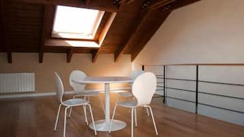 Una habitación con tragaluz, vigas de madera, una mesa redonda con sillas y un radiador blanco.
