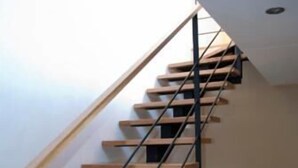 A staircase with wooden steps and black metal railings. - Residencial Massana (Alcala de la Selva)