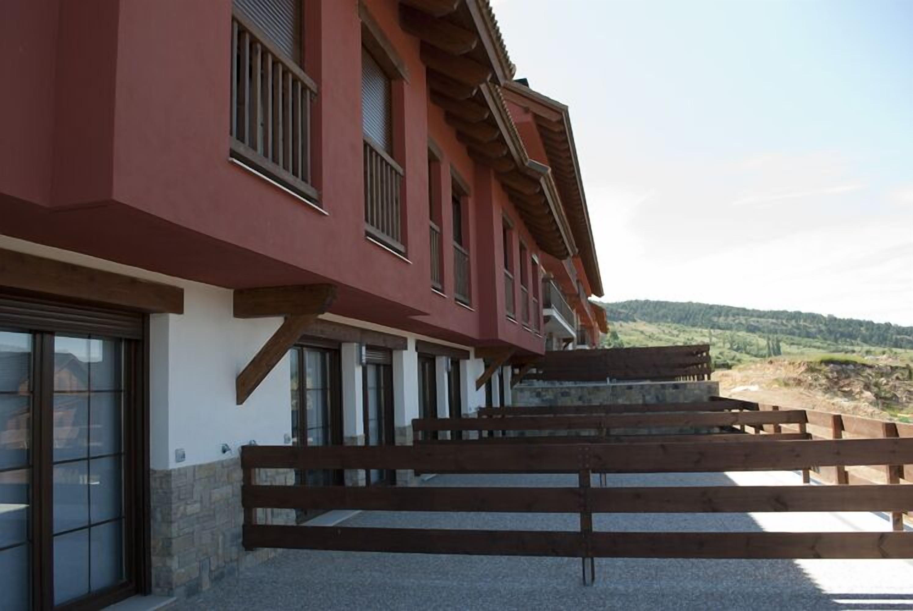 Un edificio con fachada roja, varias ventanas y una terraza de madera.