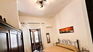 Une chambre à coucher avec un lit, une armoire, un tableau et une porte donnant sur une autre pièce.
