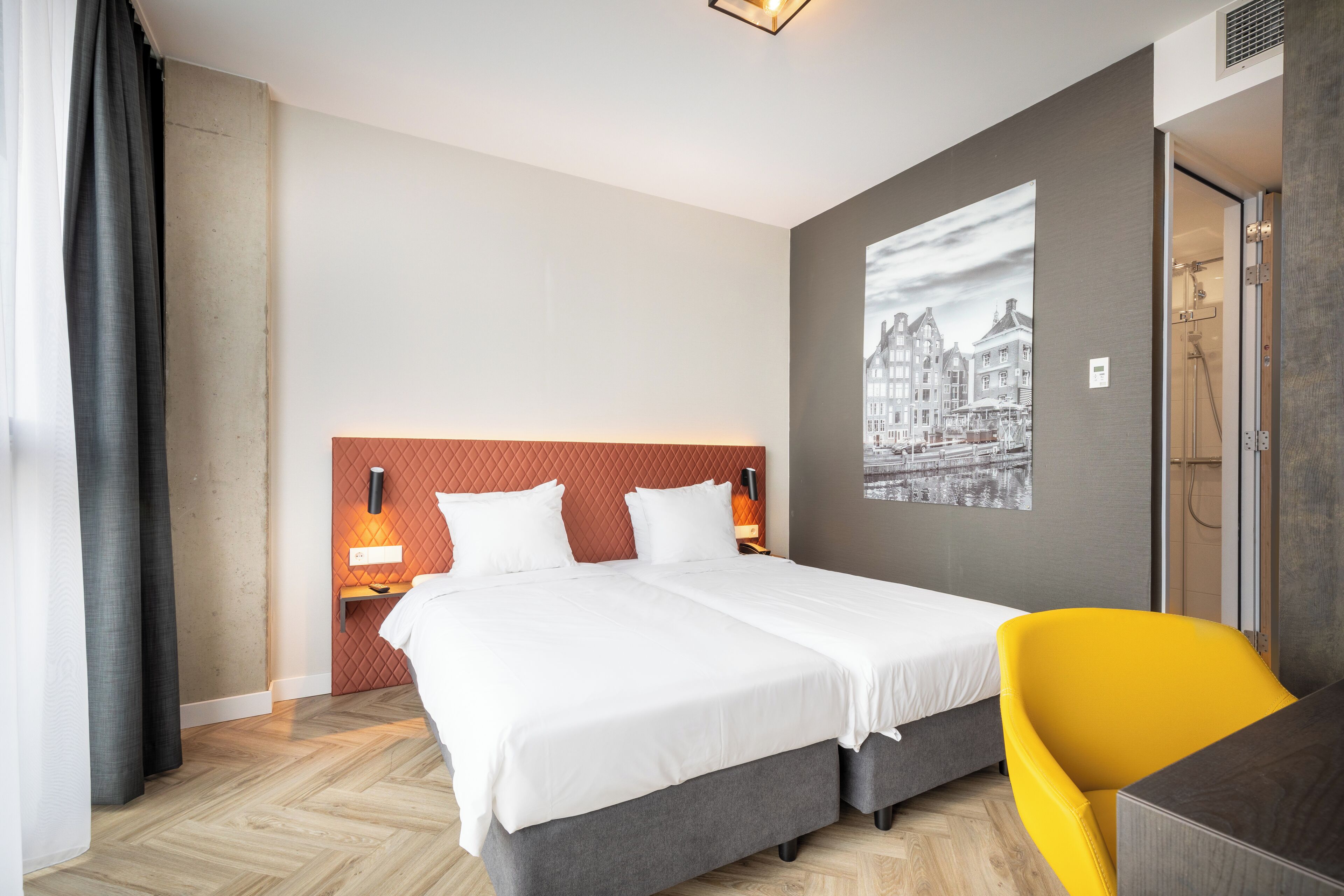 Una habitación de hotel con una cama grande, un escritorio, una silla y un cuadro colgado en la pared.