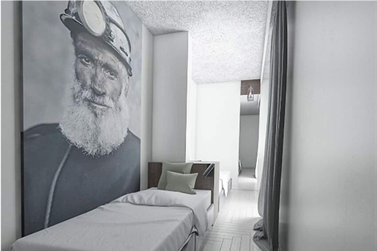 A modern hotel room with a large bed, a headboard with a mural, a walk-in closet, and a hallway leading to another room.
