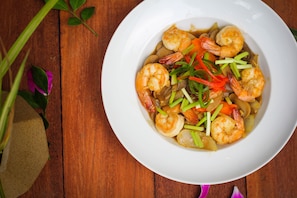 A white plate of shrimp and vegetables on a wooden table. - Popular Hotel & Spa (Siem Reap)