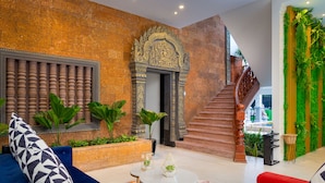A modern lobby with a stone wall, a staircase, and a seating area with blue and red sofas. - Popular Hotel & Spa (Siem Reap)