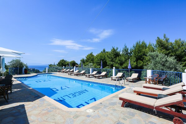 Une piscine avec des chaises longues et vue sur la mer.
