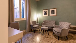 Et værelse med spisebord, to lænestole, en sofa, en gulvlampe og to billeder hængende på væggen.